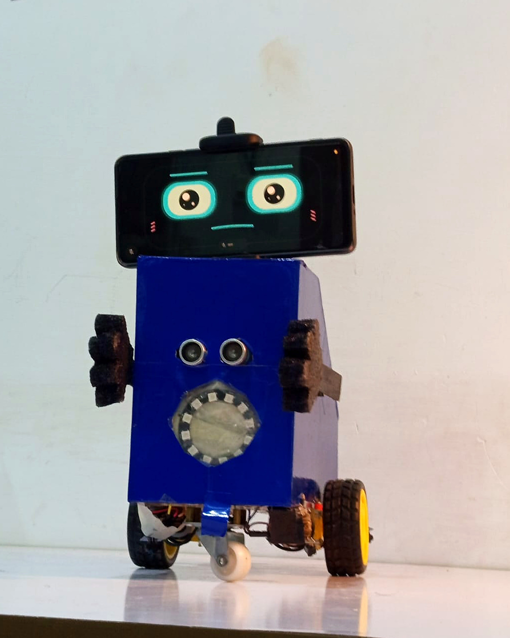 AMSAN V1.0 viewed from the front at an angle with its smartphone face, blue body, front sensors and wheels visible.